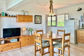 A modern kitchen with wooden cabinets, a dining table with chairs, a television, and a refrigerator. - Holiday home in Fuencaliente for 3 (Fuencaliente, La Palma)