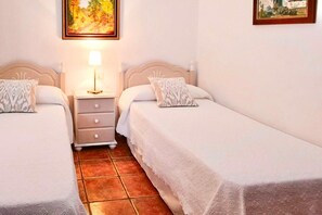 A twin room with two beds, a nightstand, and a painting on the wall. - Holiday home in Fuencaliente for 3 (Fuencaliente, La Palma)