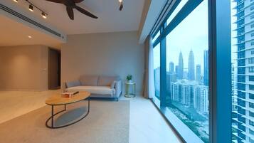 A modern living room with a sofa, a coffee table, and a view of a cityscape through large windows.