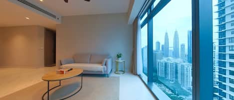 A modern living room with a sofa, a coffee table, and a view of a cityscape through large windows.