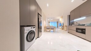 Eine moderne Küche mit Einbauwaschmaschine, einem Essbereich mit Tisch und Stühlen sowie einer Küchenarbeitsplatte mit Geräten.