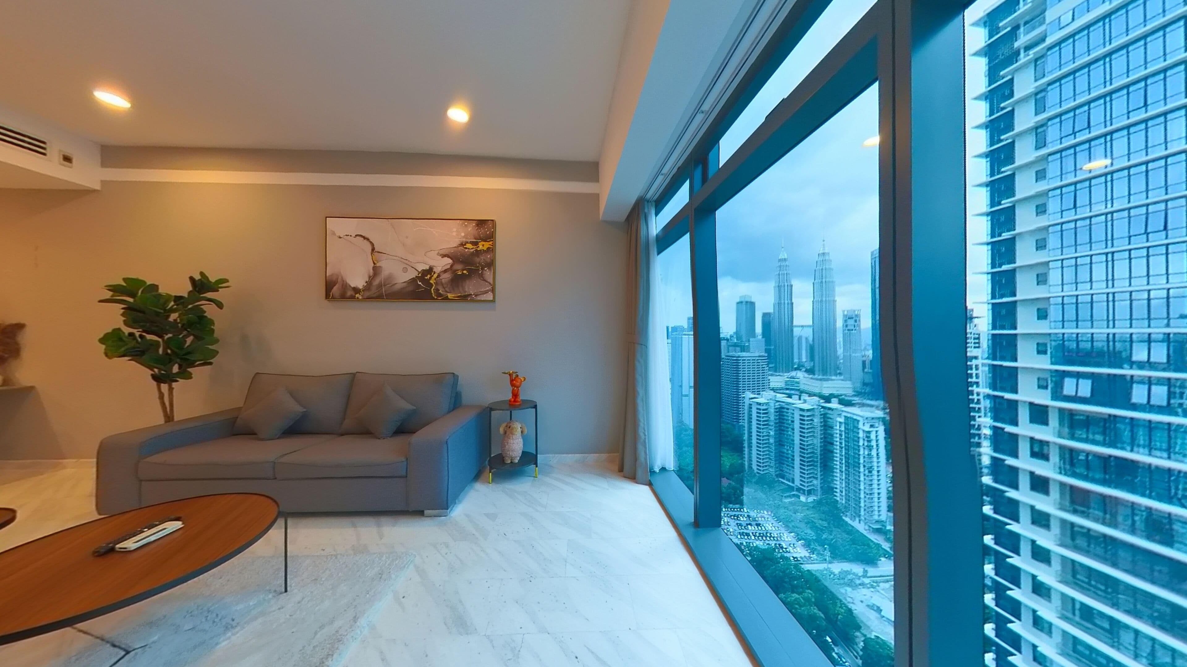 A modern living room with a sofa, a small table, and a large window with a cityscape view.