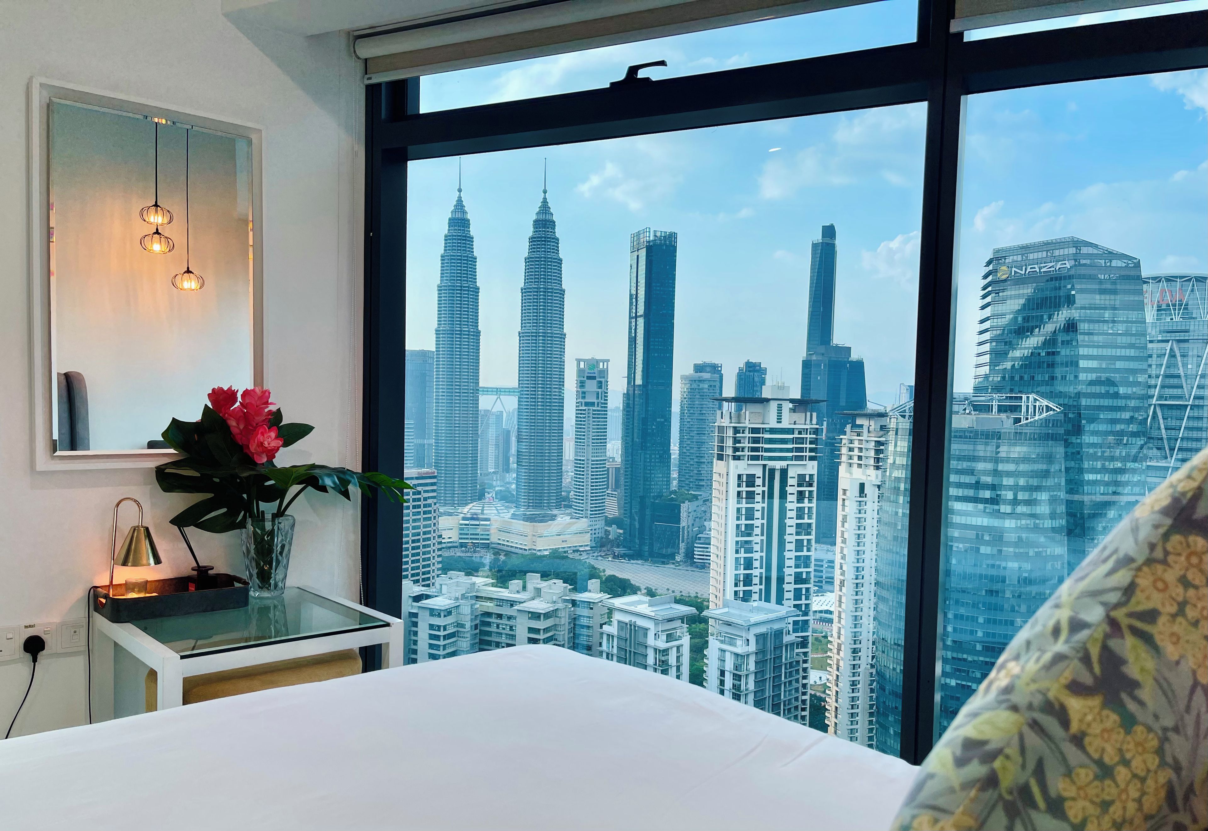 A hotel room with a large window offering a view of the city's skyline, including prominent skyscrapers.