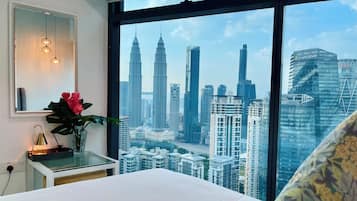 A hotel room with a large window offering a view of the city's skyline, including prominent skyscrapers.