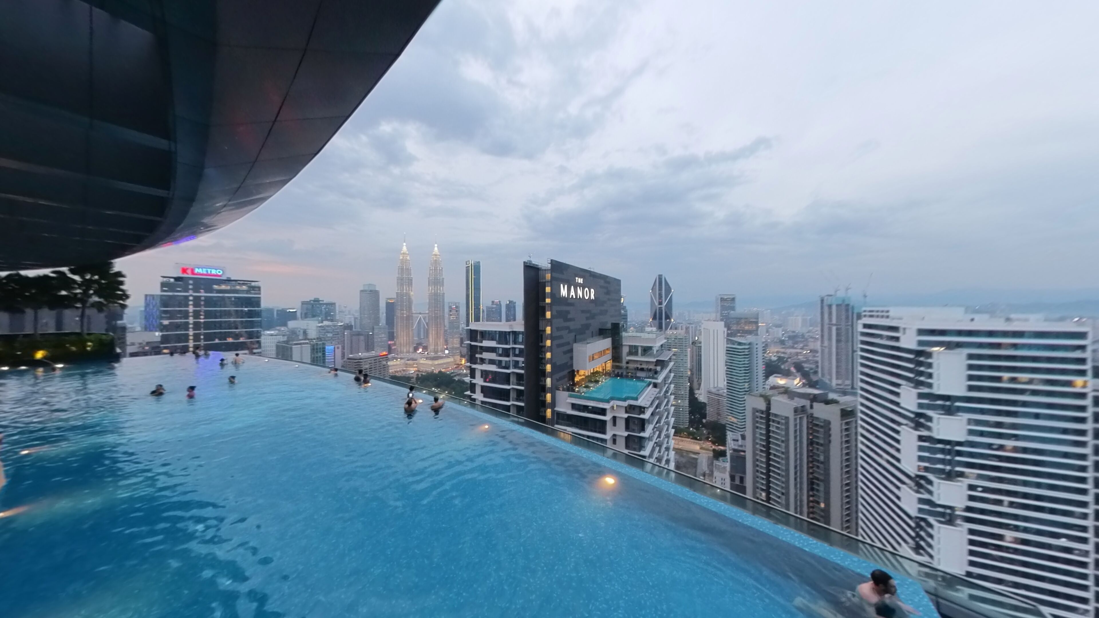 Een overloopzwembad met uitzicht op de skyline van de stad, waaronder de Petronas Towers.