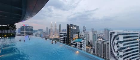 An infinity pool with a city skyline view, including the Petronas Towers.