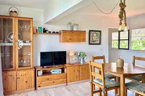 Une cuisine chaleureuse avec des meubles en bois, un téléviseur et un coin repas comprenant une table et des chaises.