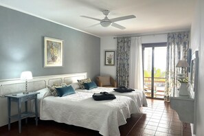A bedroom with two beds, a ceiling fan, a nightstand, and a view of the outdoors. - Apartment in Radazul by the sea (Radazul)