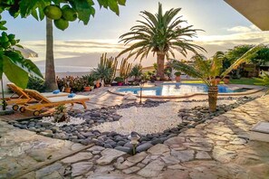 A pool area with lounge chairs, palm trees, and a variety of plants. - Apartment in Radazul by the sea (Radazul)