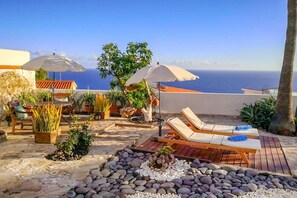 A rooftop patio with lounge chairs, potted plants, and umbrellas overlooking the sea. - Apartment in Radazul by the sea (Radazul)