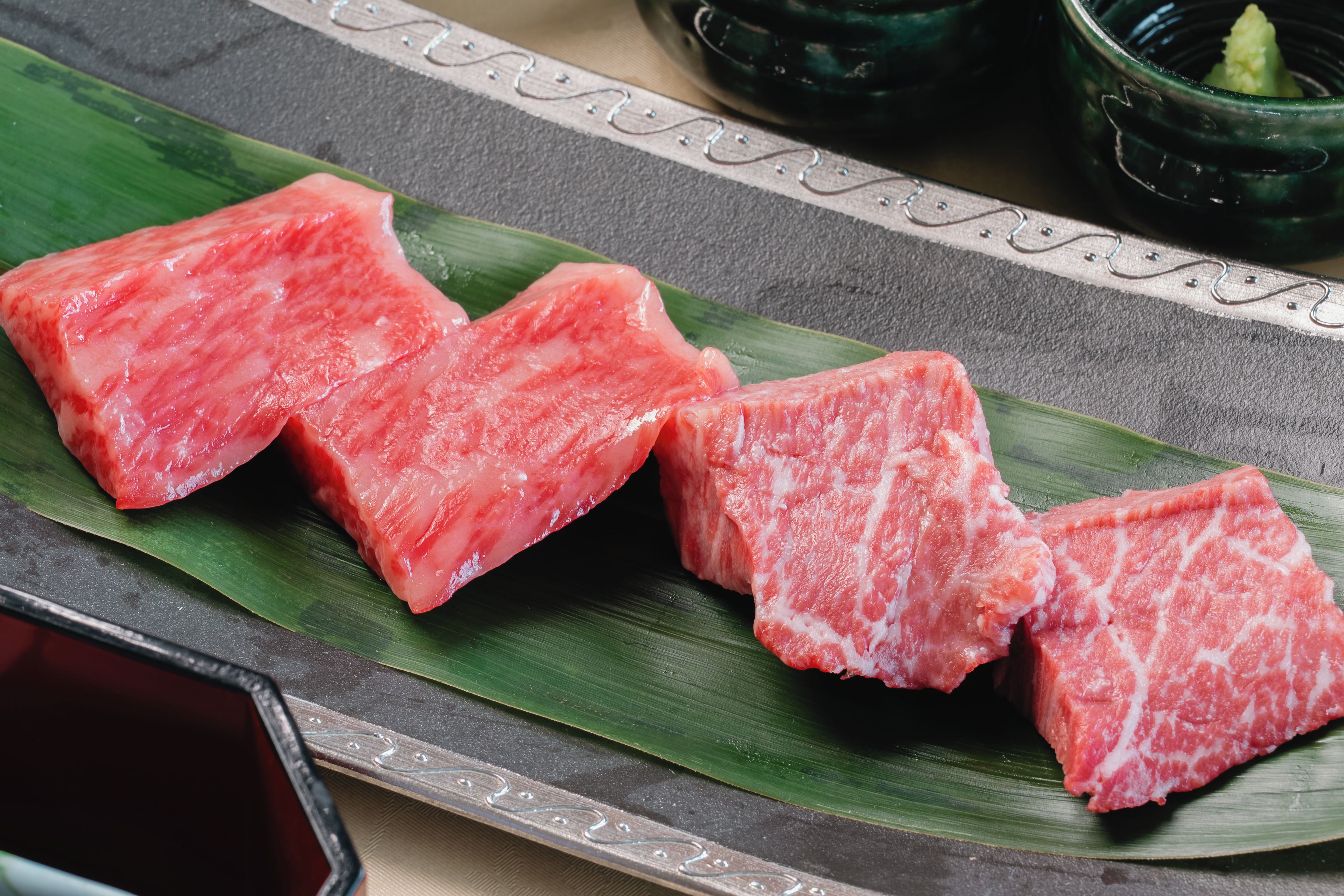 A plate of raw fish on a leaf with a decorative border.