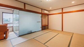 A room with tatami flooring, a sliding glass door, a cushioned chair, and a ceiling light fixture. - Fleurs Resort & Hotel (Nishio)