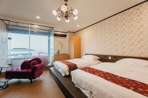Habitación de hotel con dos camas, un ventanal grande, una silla morada y un candelabro.