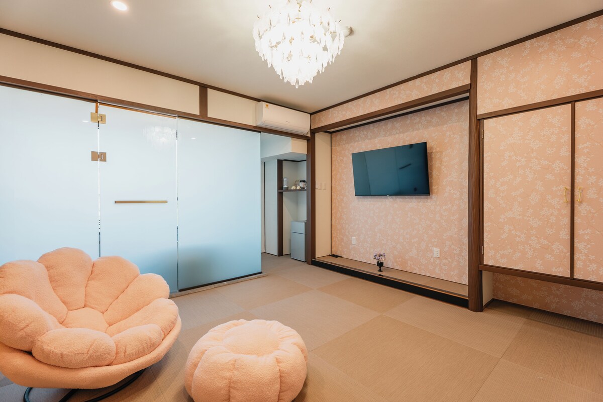 Una habitación moderna con una televisión de pantalla plana en la pared, un sillón mullido y un pequeño reposapiés.