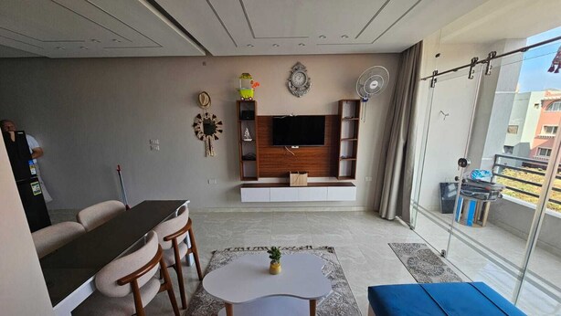 Un soggiorno moderno con zona pranzo, televisione a schermo piatto e balcone con vista.