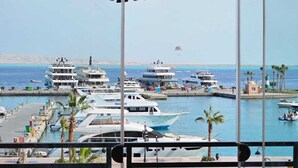 Una marina con diverse imbarcazioni ormeggiate, cielo sereno e vista sul mare.