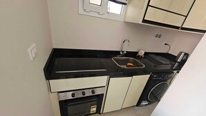Una cucina compatta con fornello, forno, lavello e una piccola finestra.