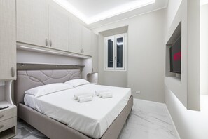 A modern bedroom with a bed, built-in wardrobe, bedside table, and a TV mounted on the wall. - [15 min - Old Bridge] Suite FI (Florence)