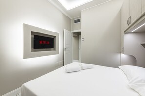 A hotel room with a bed, a wall-mounted TV displaying 'NETFLIX', and a door leading to a closet. - [15 min - Old Bridge] Suite FI (Florence)