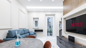En moderne stue med et spisebord, sofaer, et fladskærms-tv og en pejs.