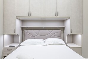Een slaapkamer met een bed, nachtkastjes en inbouwkasten.
