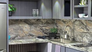 Una cocina moderna con protector de encimera de mármol, pileta de acero inoxidable y taburetes de bar.