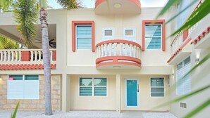 Un edificio de dos pisos con un balcón, una puerta azul y fachada de piedra.