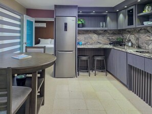 Eine kompakte Küche mit integriertem Kühlschrank, einer Spüle und einem Essbereich mit Tisch und Stühlen.