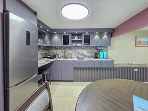A modern kitchen with built-in appliances, a marble backsplash, and a dining area with a wooden table. - Bahía Bonita | Cozy Cabo Rojo Retreat (Cabo Rojo)