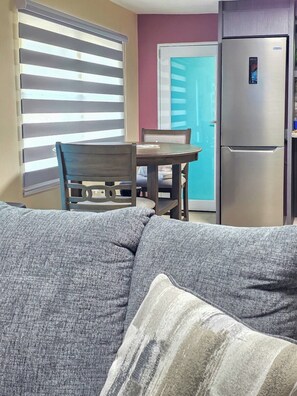 Ein Wohnzimmer mit einer Couch, einem Holztisch und einem Kühlschrank.