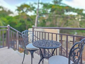 A balcony with a metal railing, two chairs, and a small round table. - Brisa Del Caribe | Top Floor Studio in Cabo Rojo (Cabo Rojo)