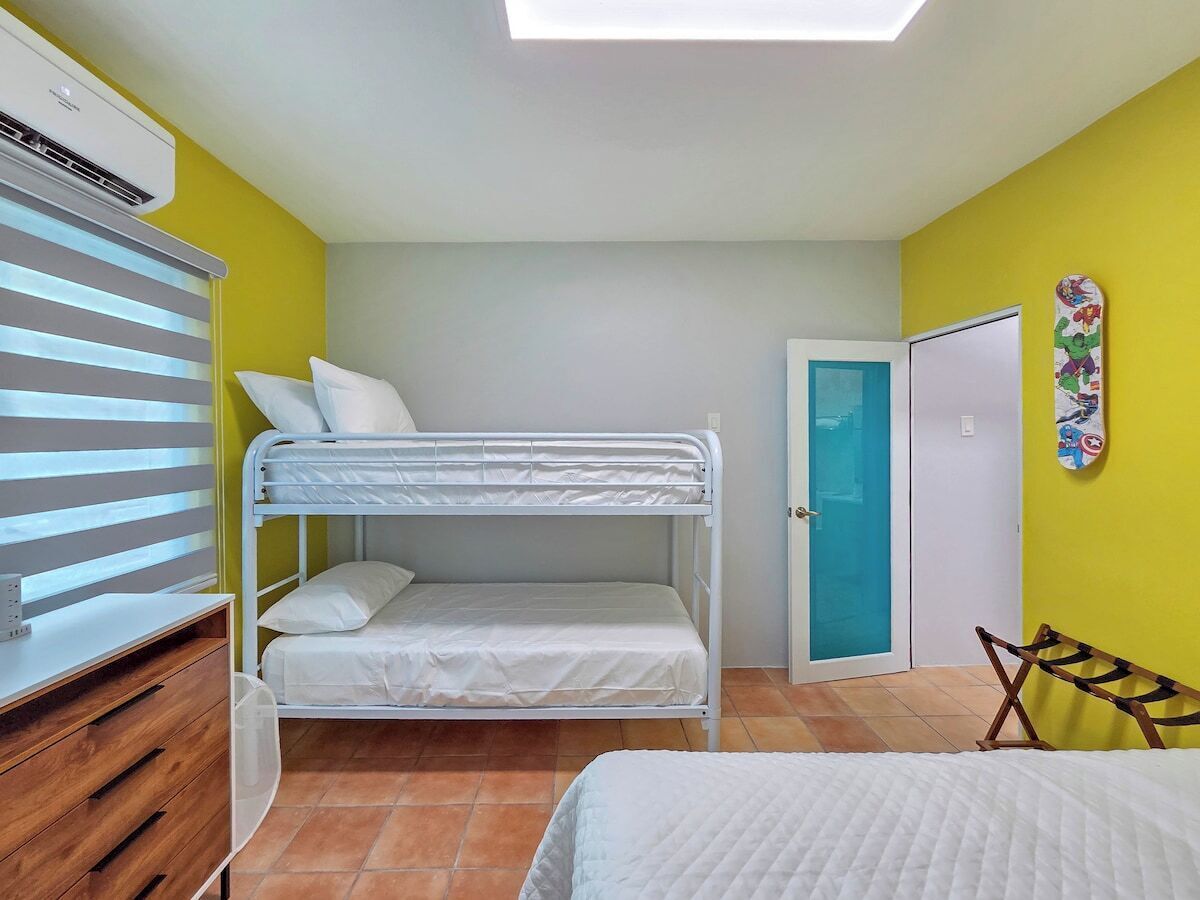 A bunk bed room with a desk, a wardrobe, and a door.
