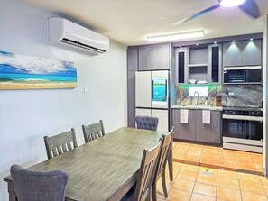 Ein Essbereich mit Holztisch und -stühlen, eine Küche mit modernen Geräten und ein Bild an der Wand.