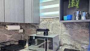 A modern kitchen with a built-in microwave, a black induction cooktop, and a stainless steel sink. - Palmera Azul | Cozy Private Apartment in Cabo Rojo (Cabo Rojo)