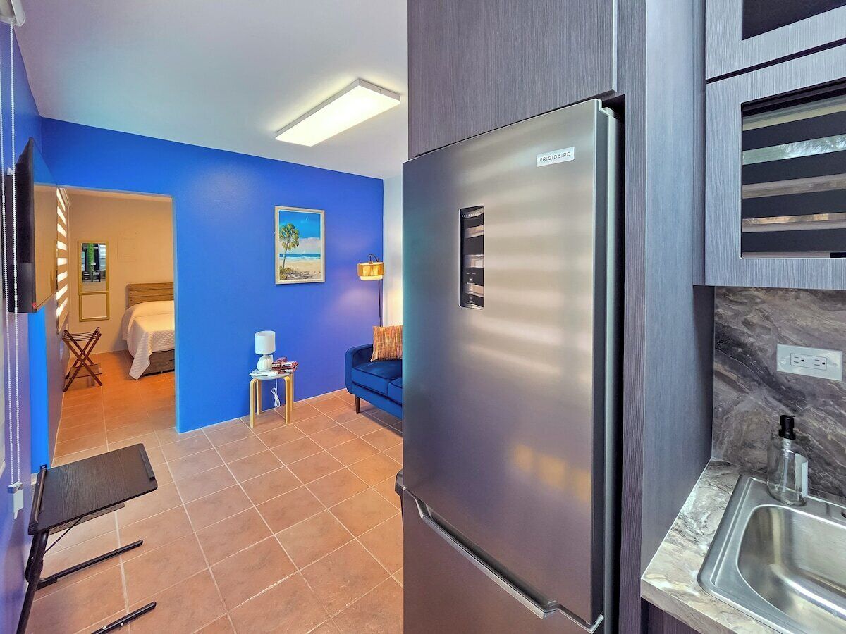 A modern kitchen with a stainless steel refrigerator, a sink, and a blue wall.