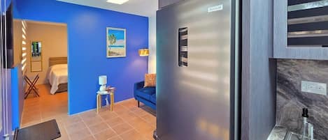 A modern kitchen with a stainless steel refrigerator, a sink, and a blue wall.