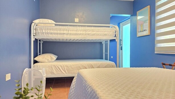 A room with bunk beds, a single bed, and a window with blinds. - Palmera Azul | Cozy Private Apartment in Cabo Rojo (Cabo Rojo)