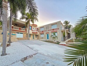 Een meerlaags hotel met een binnentuin, palmbomen en een heldere lucht.
