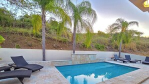 Ein Swimmingpool mit Liegestühlen und einer Steindeck.