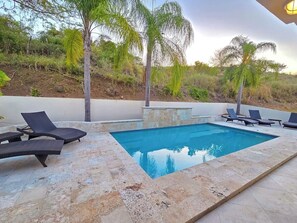 Ein Swimmingpool mit Liegestühlen und einer Steindeck.