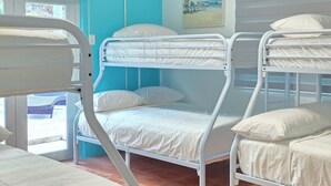 Ein Zimmer mit Etagenbetten, einem Fenster und einer Tür, die nach draußen führt.
