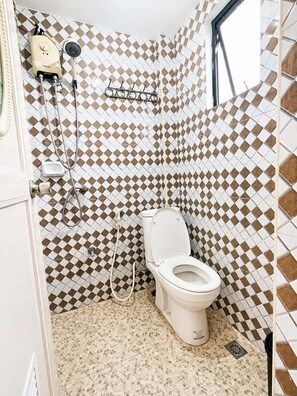 A bathroom with a toilet, a shower, and a hand dryer. - Metrohive Apartment 2D - Cozy Studio Near Airport & PITX (Pasay City)