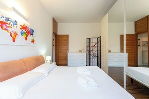 A hotel room with a large bed, a bedside table with a lamp, a wardrobe, a mirror, and a world map artwork on the wall. - Apartment in Milan with 1 bedrooms sleeps 2 (Milan)