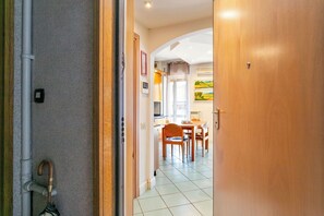 A hallway leading to a dining area with a table and chairs, a wooden door, and a tiled floor. - Apartment in Milan with 1 bedrooms sleeps 2 (Milan)