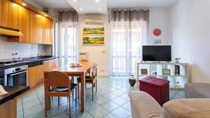 Una cocina moderna con comedor, televisor de pantalla plana y sala de estar con sofá.