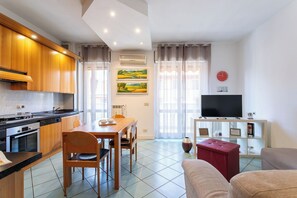 Eine moderne Küche mit Essbereich, einem Flachbildfernseher und einem Wohnzimmer mit Sofa.