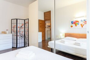 A hotel room with a bed, a bedside table, a mirror, a wardrobe, and a view into the kitchen. - Apartment in Milan with 1 bedrooms sleeps 2 (Milan)
