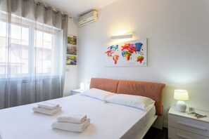Ein Hotelzimmer mit einem Bett, einem Nachttisch, einer Lampe und einem Wandbild einer Weltkarte.