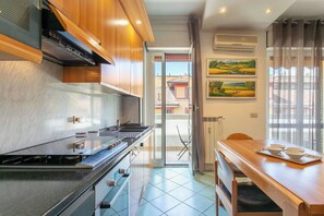 A modern kitchen with a stove, sink, and wooden cabinets. There is a dining area with a table and chairs, and a window with curtains. - Apartment in Milan with 1 bedrooms sleeps 2 (Milan)