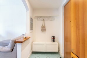 A hallway with a white bench, a wooden door, and a wall-mounted shelf with a bag and a framed picture. - Apartment in Milan with 1 bedrooms sleeps 2 (Milan)